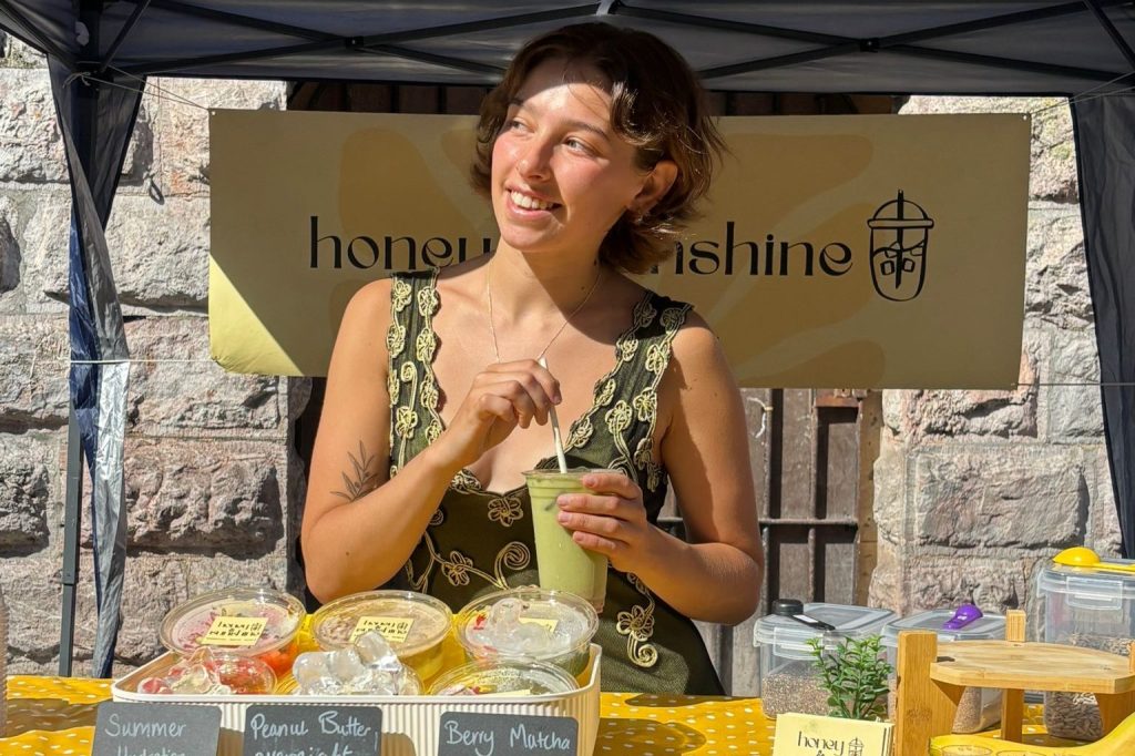 Olivia at the honey & sunshine market stall with a vegan iced matcha latte